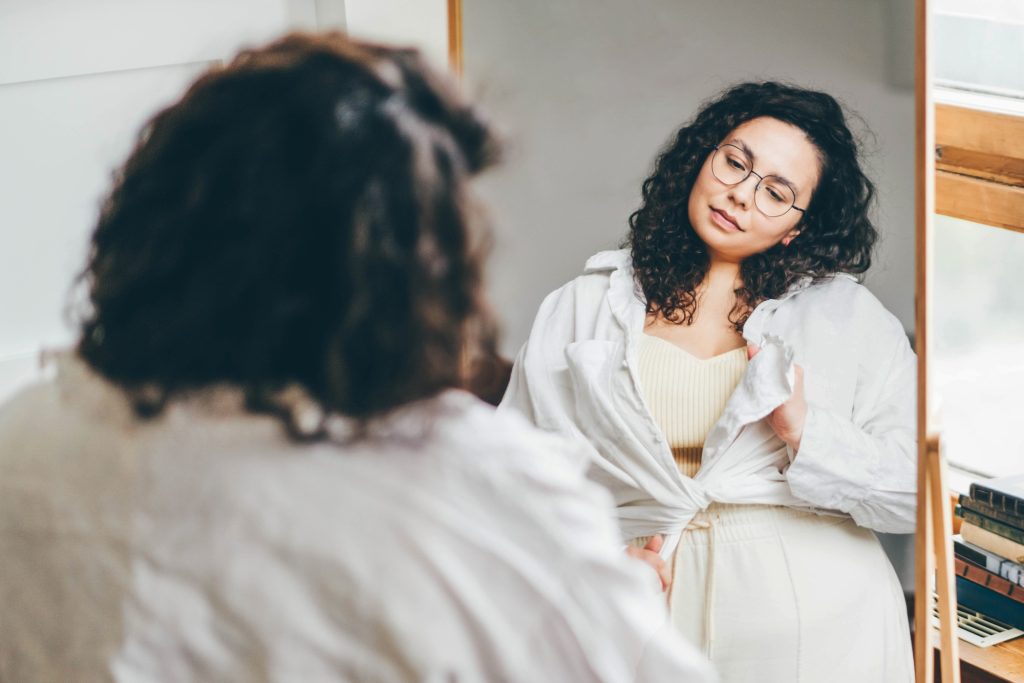 Une femme avec des cheveux volumineux se regardent dans le miroir